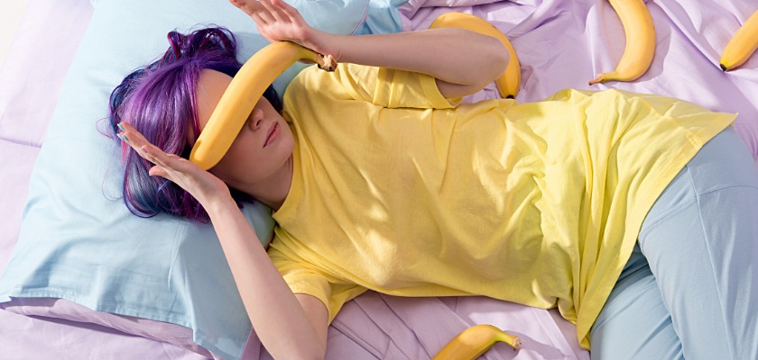 Vista ad alto angolo di una giovane donna sdraiata a letto con diverse banane sparse sulle lenzuola – Pene
