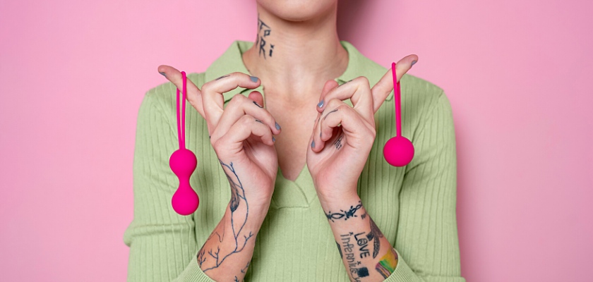 Primo piano di una donna che tiene in mano due giocattoli sessuali color rosa – Sex Toys per coppia